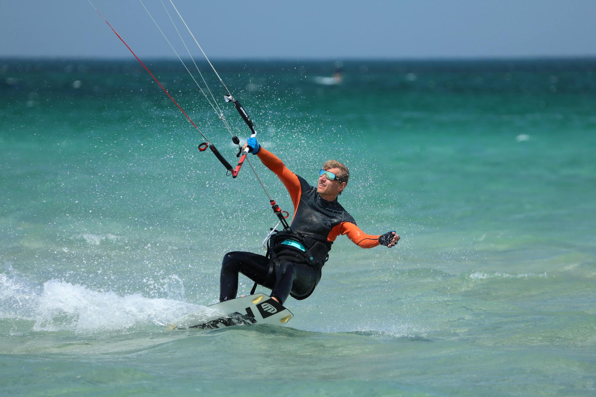 A man wearing a wetsuit skillfully kiteboarding across ocean waves on a sunny day.