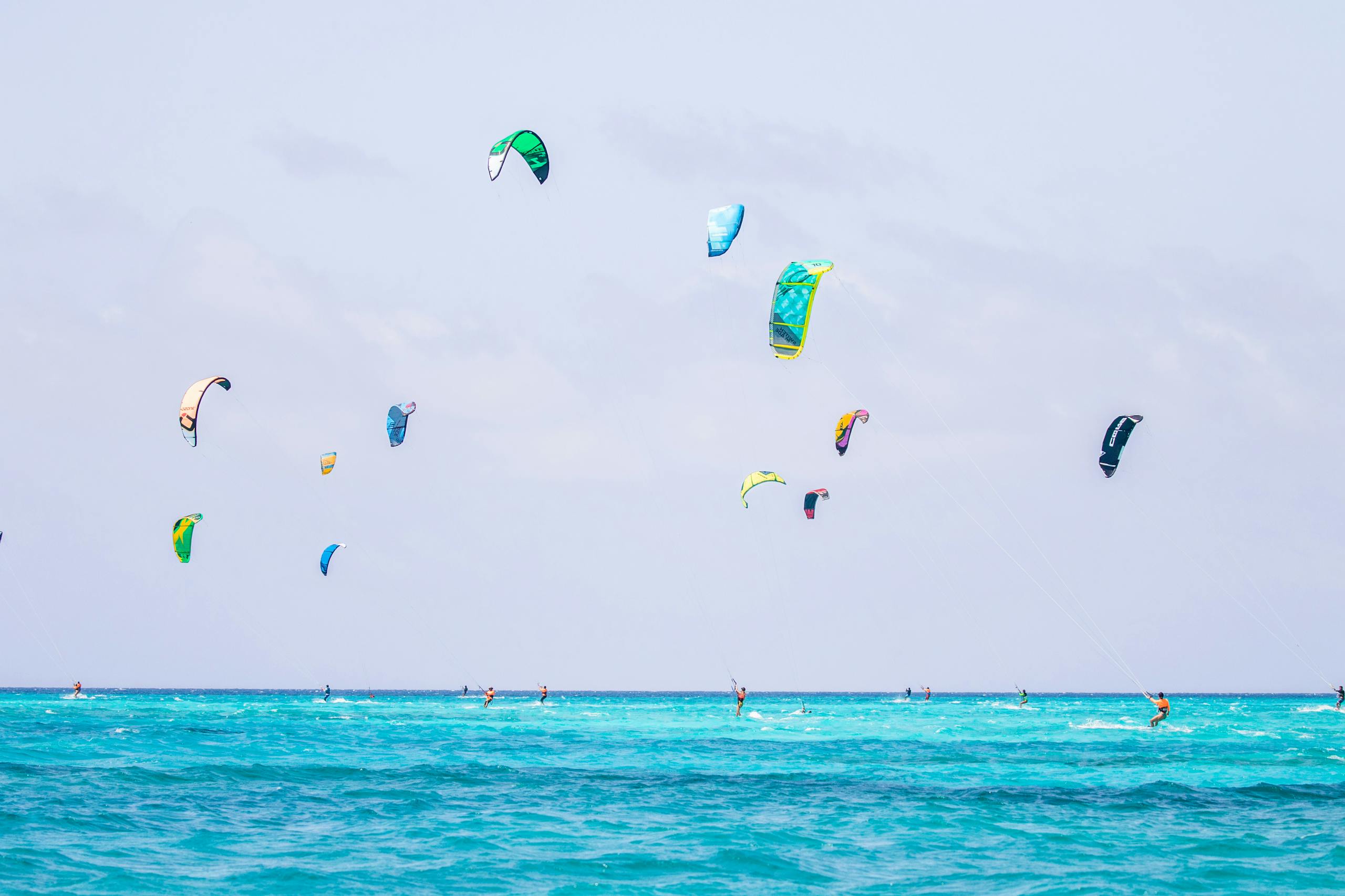 A vibrant scene of kiteboarders gliding on turquoise waters, capturing summer leisure and excitement.