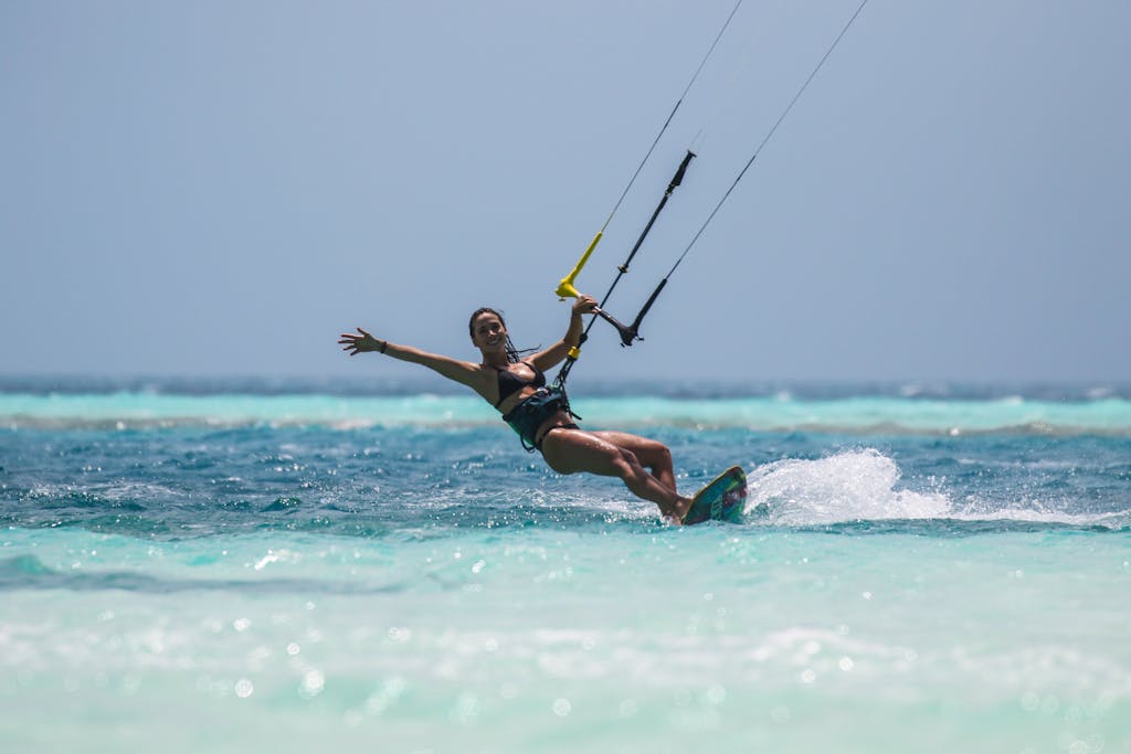 Woman enjoying kiteboarding in clear turquoise waters on a sunny day.