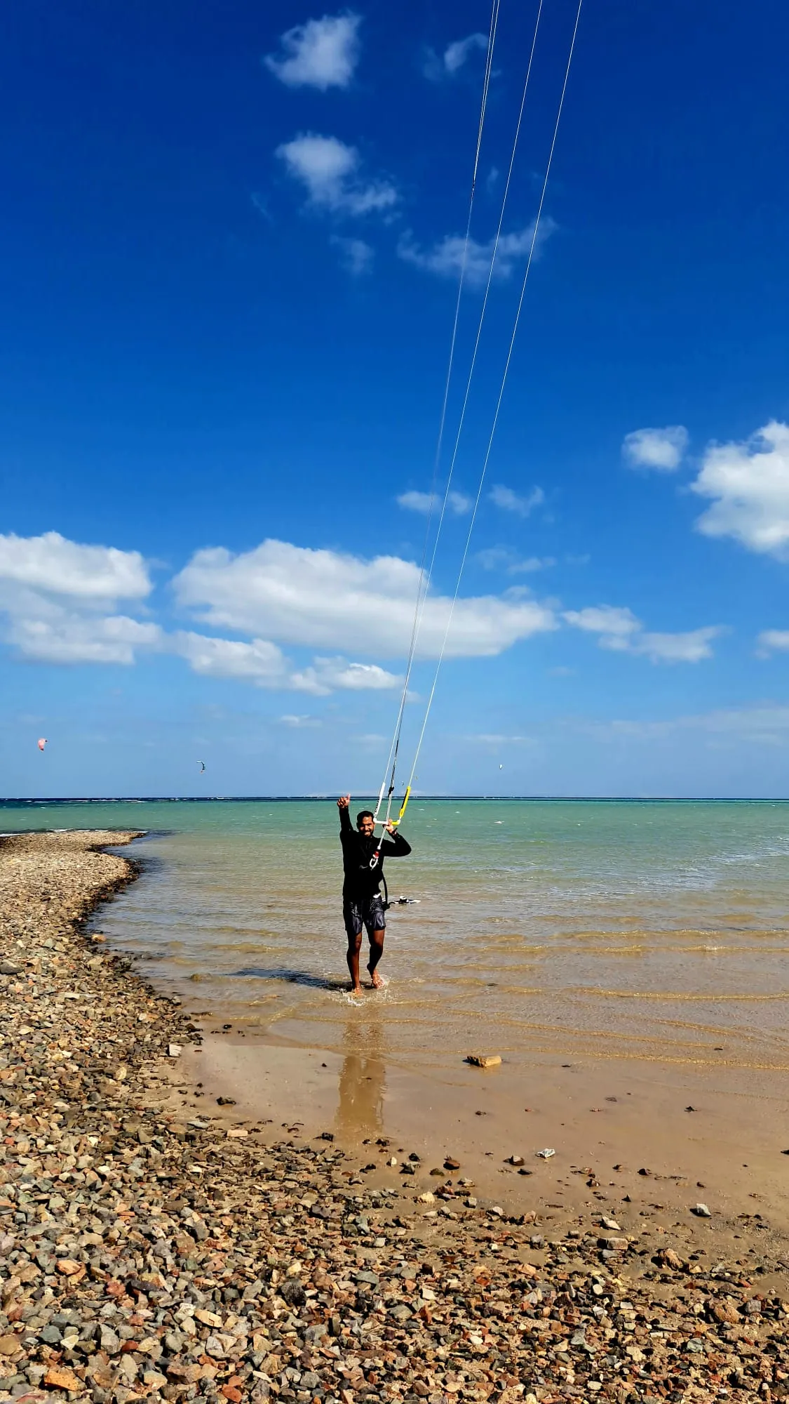 A group of people learning kitesurfing in the sea with vibrant kites and safety gear on a sunny day.